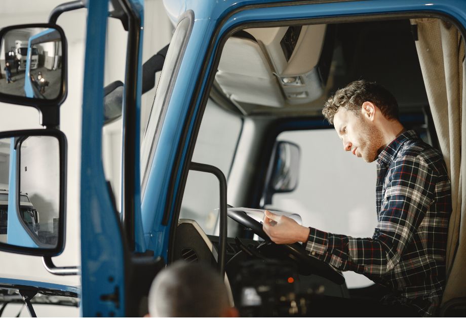 man sitting in truck cabin, reading documents